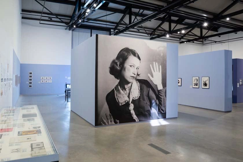 The picture showThe picture shows part of the Feminist Avant-Garde exhibition in Arles. The exhibition areas are in shades of blue and purple, which create a nice contrast to the works of art, which are mostly in black and white. s a part of the Feminist Avant-garde exhibition in Arles. The exhibition areas are in shades of blue and purple, which create a nice contrast to the artworks, which are mostly in black and white.