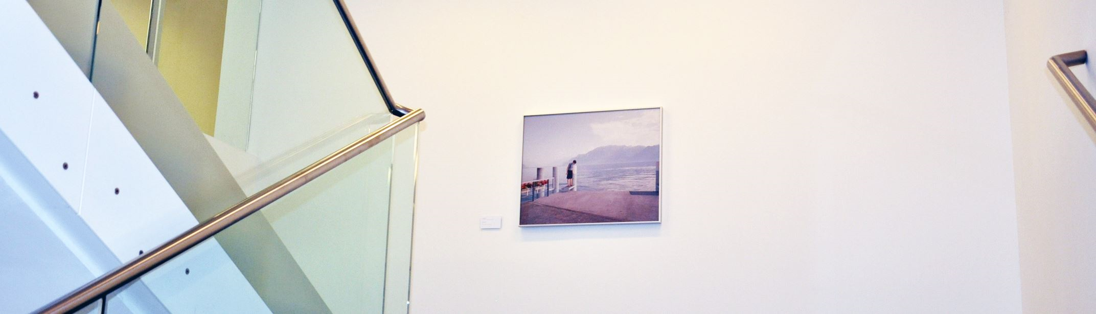 Ecke eines hellen Raumes mit einer Kunstinstallation, an der Wand hängt ein Bild mit einer Strandlandschaft.