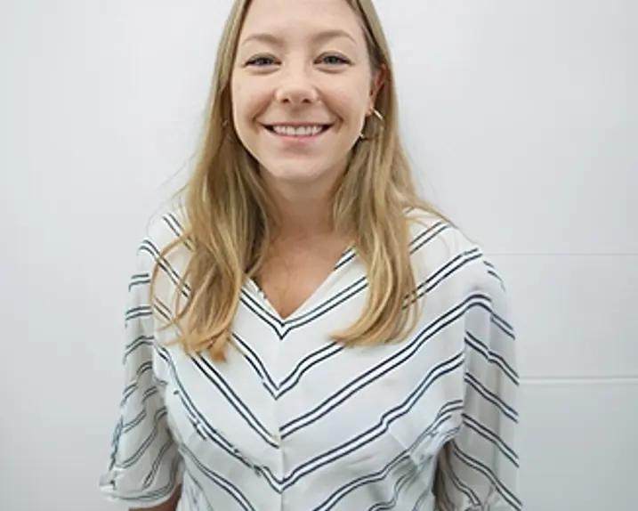 Eva Haberfellner has light-colored hair. She stands in front of a white background and smiles.