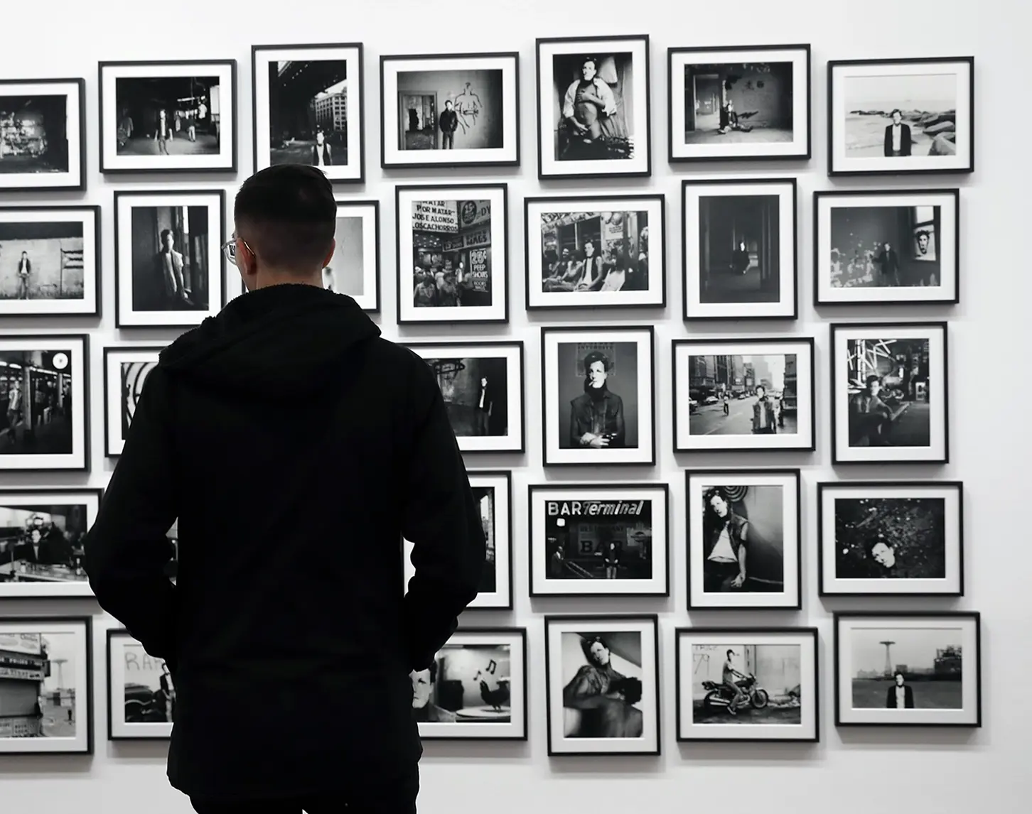 An einer weißen Wand hängt eine Foto-Installation des Künstlers David Wojanorwicz, die verschiedene Aspekte seines Lebens zeigt.