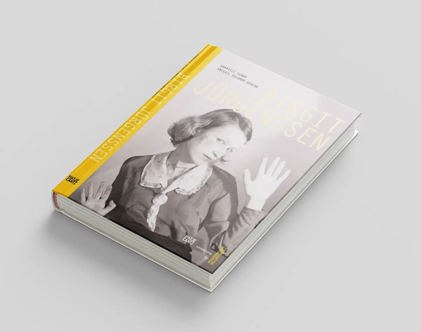 Birgit Jürgenssen's exhibition catalog from 2010 shows a photograph of a woman in black and white pressing herself against a pane of glass. The font and the spine of the book are in yellow.