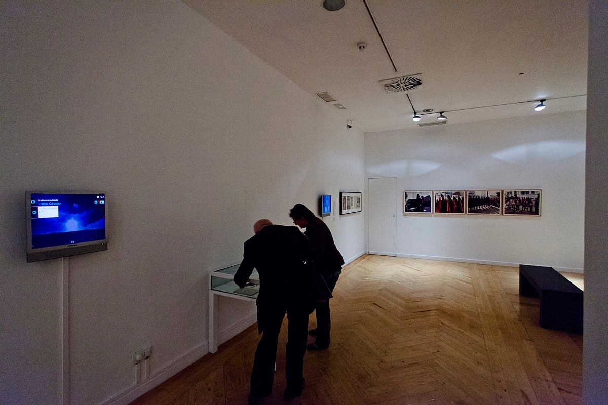 In a dark exhibition room, two people are bent over a glass display case.