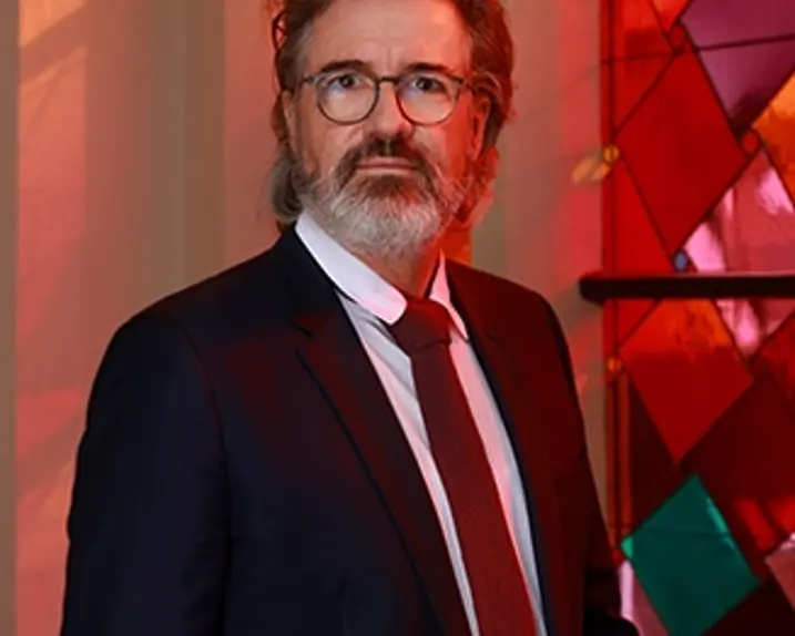 The artist Olafur Eliasson stands in front of a colorful church window in the Dome St Nikolai in Greifwald.