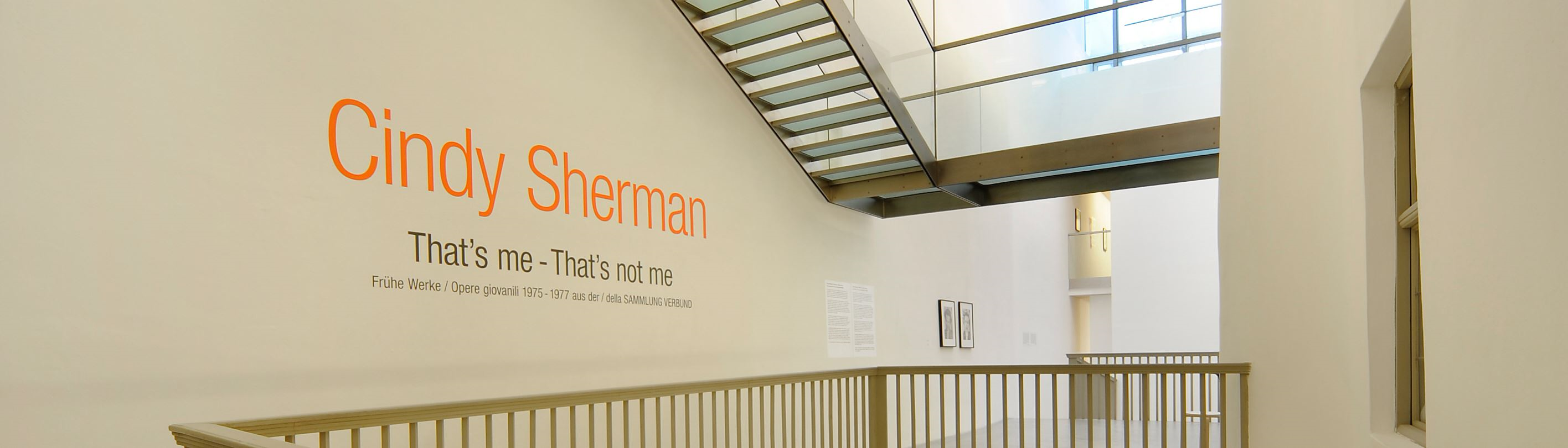 Hell erleuchtetes Treppenhaus mit dem Schriftzug der Künstlerin Cindy Sherman und dem Ausstellungstitel.
